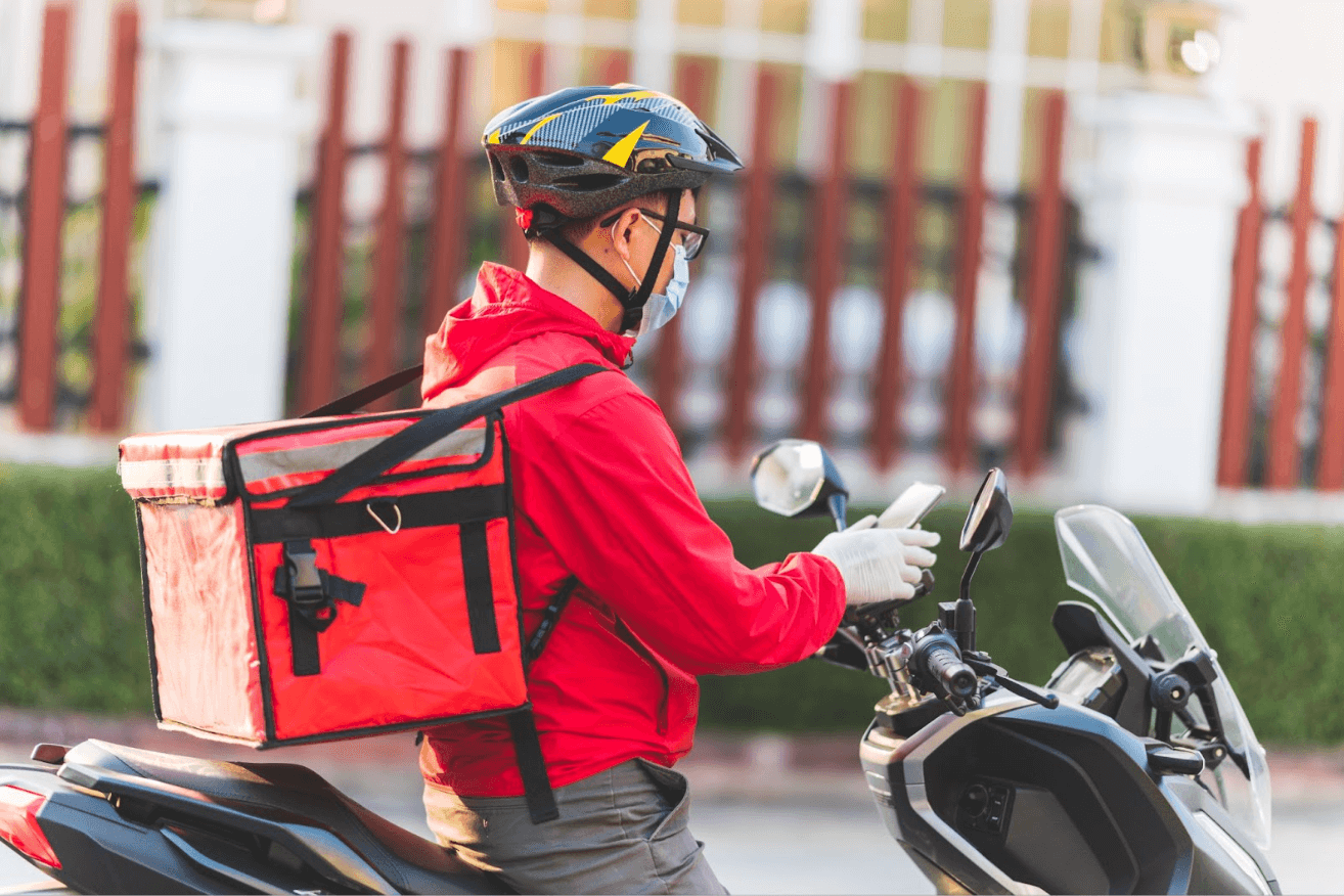 delivery driver sitting on scooter with mobile phone